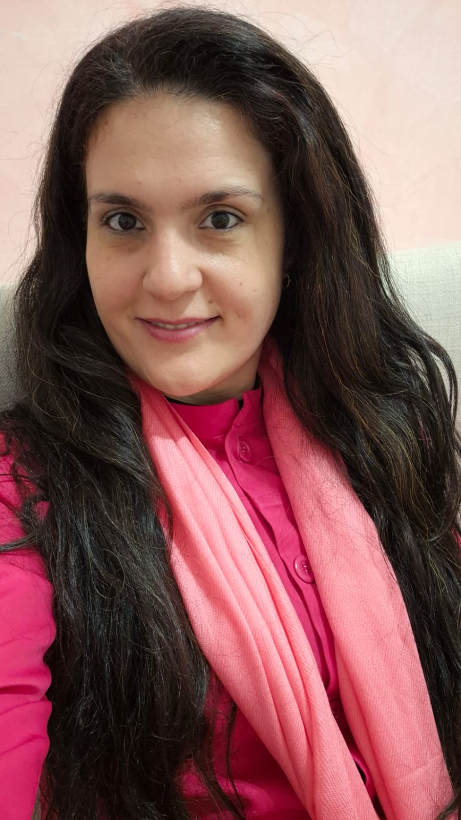 Ludimila Silveira, nutricionista sorridente com cabelos longos e cacheados, vestindo uma blusa rosa